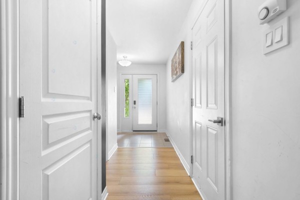 White hallway with beige tiled floor near the entrance and wood plank flooring further in. - 98 Rue De La Galère, Gatineau