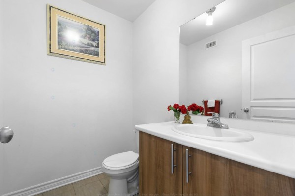 Powder room with a white toilet, vanity with wood cabinets, and a large mirror. - 98 Rue De La Galère, Gatineau