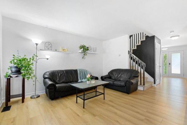 Living room with black leather sofas, a coffee table, and light wood floors. - 98 Rue De La Galère, Gatineau