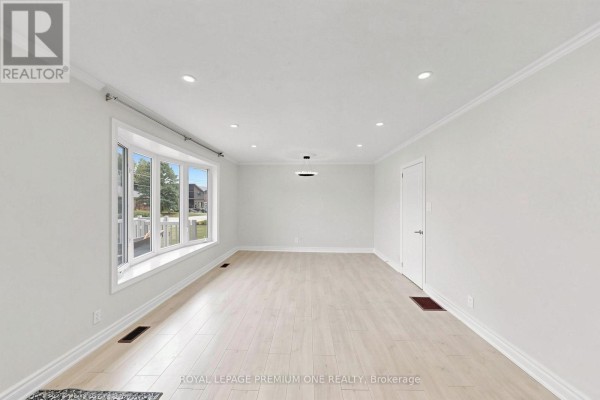 Empty living room with large bay window and light wood floors. - 98 Thornton Avenue, Bradford West Gwillimbury