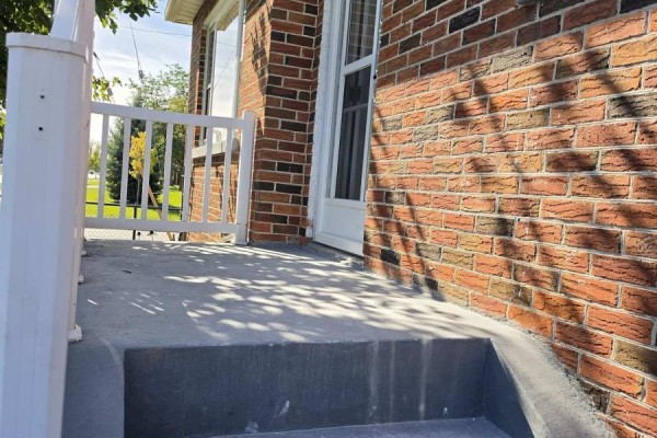 Close-up of the porch and red brick exterior wall with sunlight shadows. - 980 Glen Street, Oshawa