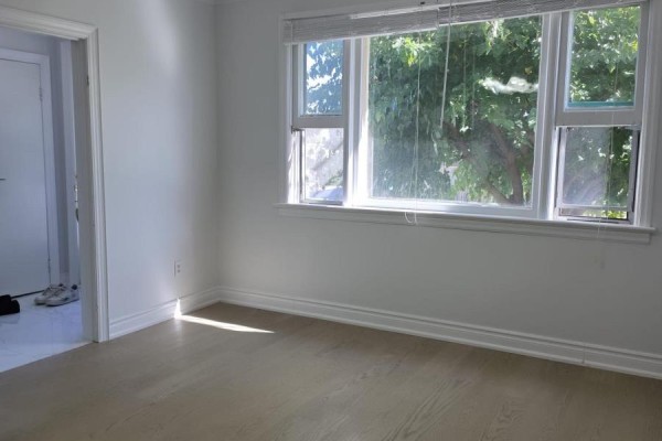 Interior room with light wood floors, white walls, and a large window overlooking trees. - 980 Glen Street, Oshawa