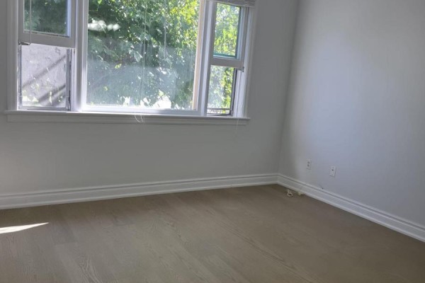 Interior room with light wood floors, white walls, and a window view of greenery. - 980 Glen Street, Oshawa