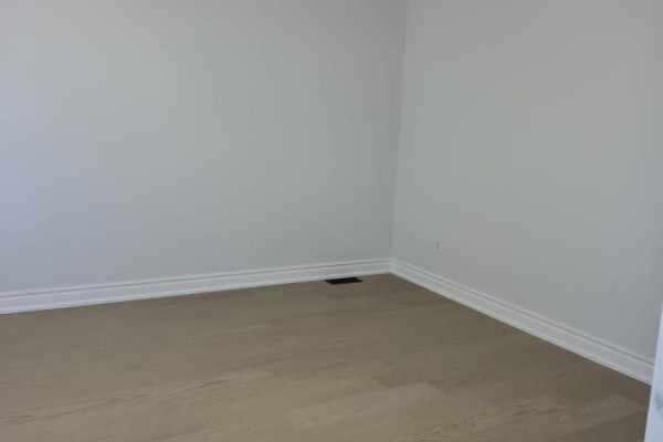 Corner of an empty room with light wood floors and white walls, showing baseboards. - 980 Glen Street, Oshawa