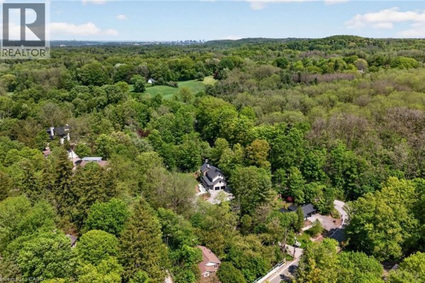 Aerial view of a residential area surrounded by dense green forest with scattered houses. - 981 Mineral Springs Road, Ancaster