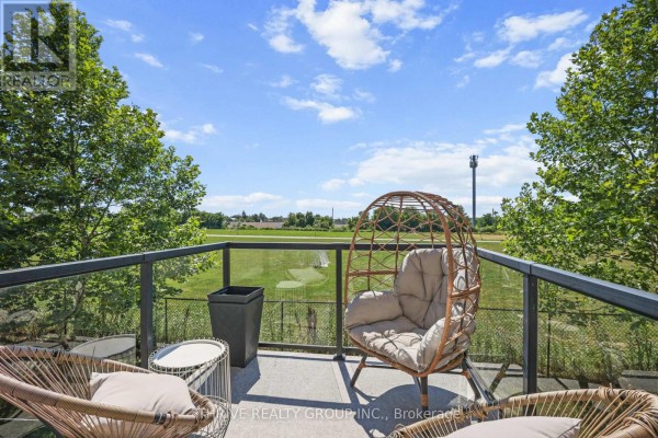 Balcony with wicker chairs and a large egg chair overlooking a green field. - 981 West Village Square, London North