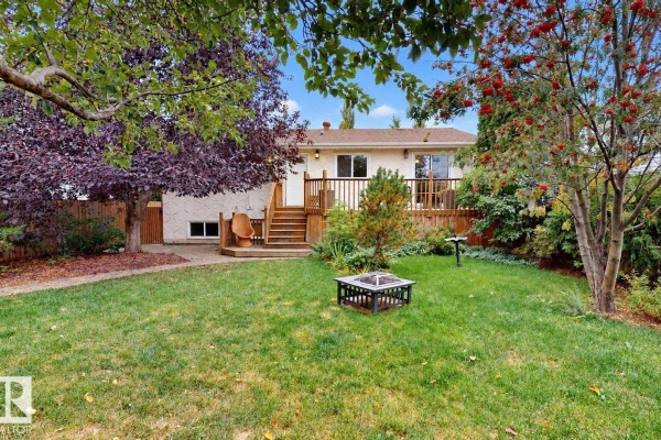 A finished basement living area with a green carpet, white doors, and a fireplace. - 9813 152 St Nw, Edmonton