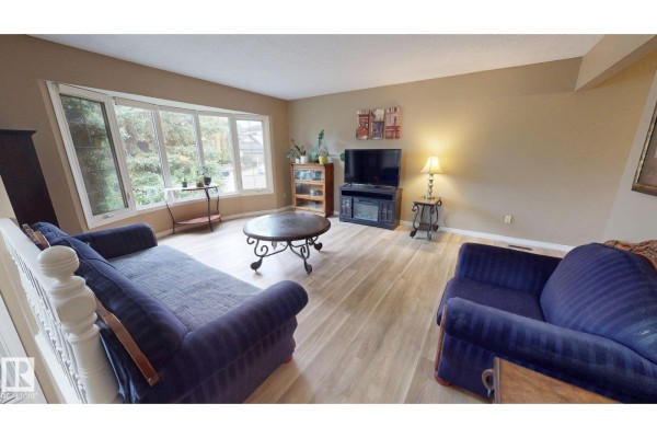 A finished basement living space with a green carpet, fireplace, and a small kitchen area. - 9813 152 St Nw, Edmonton