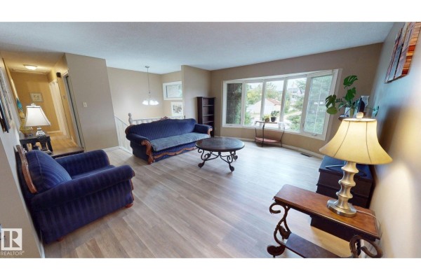A stainless steel refrigerator in a kitchen with light gray cabinets and a tile backsplash. - 9813 152 St Nw, Edmonton