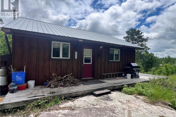 Exterior view of a rustic wooden cottage with a covered deck and burgundy door. - 982 Musky Bay Road, St  Charles