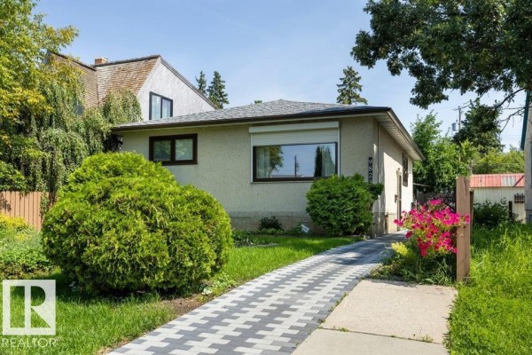Rear exterior of a bungalow with a back door and a patio with outdoor furniture. - 9823 151 St Nw, Edmonton