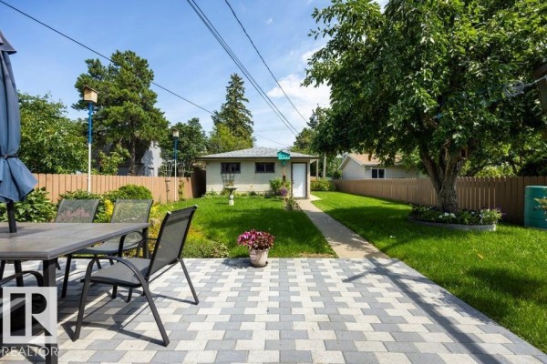Backyard view of a detached garage or shed with a white door and a birdhouse. - 9823 151 St Nw, Edmonton