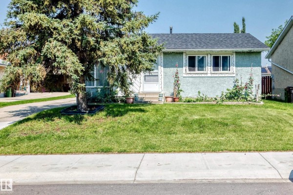 Wide angle exterior of a light blue stucco bungalow with a well-maintained front lawn. - 9824 171 Av Nw, Edmonton