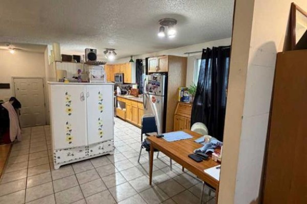 Open concept kitchen and dining area with tiled floor and wooden cabinets. - 9835 96 Avenue, Grande Prairie