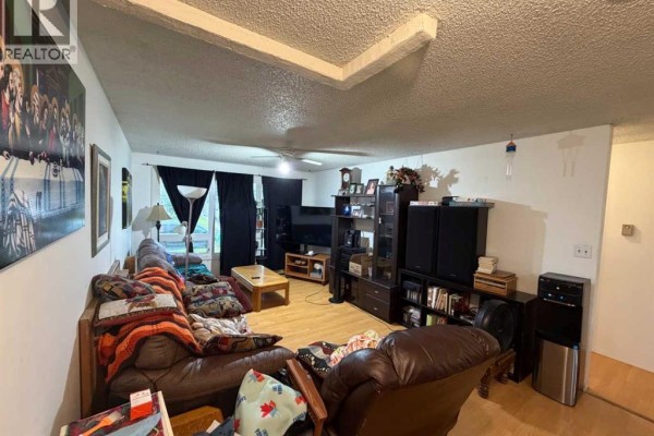 Spacious living room with plush seating, wooden floors, and large windows. - 9835 96 Avenue, Grande Prairie