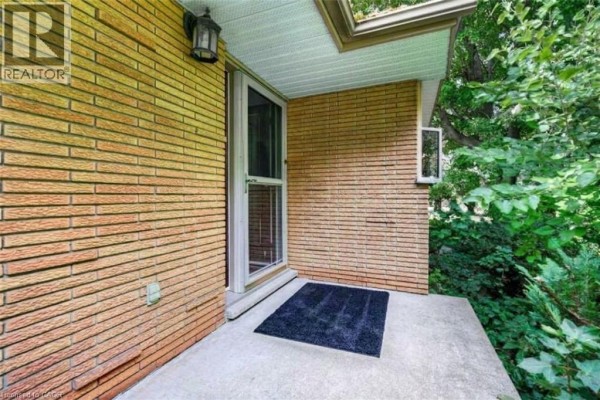 Front door of a house with brick exterior, concrete porch, and screen door. - 984 #8 Highway, Stoney Creek