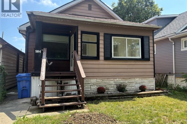 Close-up of wooden porch steps and the front entrance of the duplex with a blue recycling bin. - 984 Ellrose, Windsor