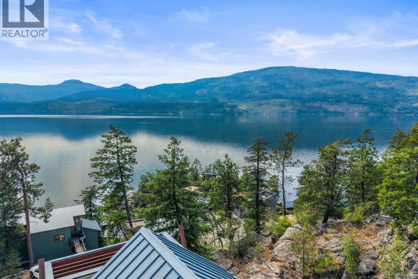View from a balcony looking out over trees and a blue lake on a cloudy day. - 9845 Eastside Road Unit# 158, Vernon