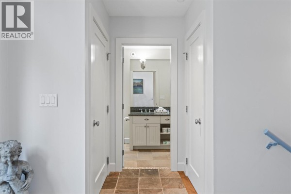 Bedroom with a king-size bed, dark dresser, and access to a kitchen area. - 9845 Eastside Road Unit# 158, Vernon