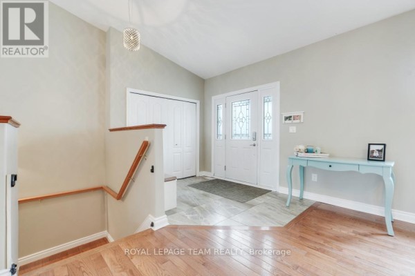 Interior foyer with light gray walls, tiled floor, double closet, and hardwood stairs. - 986 South Gower Drive, North Grenville