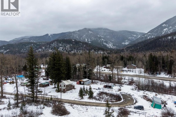 Distant view of the property and surrounding landscape featuring snow-covered mountains and trees. - 9898 Victoria Street, Hosmer