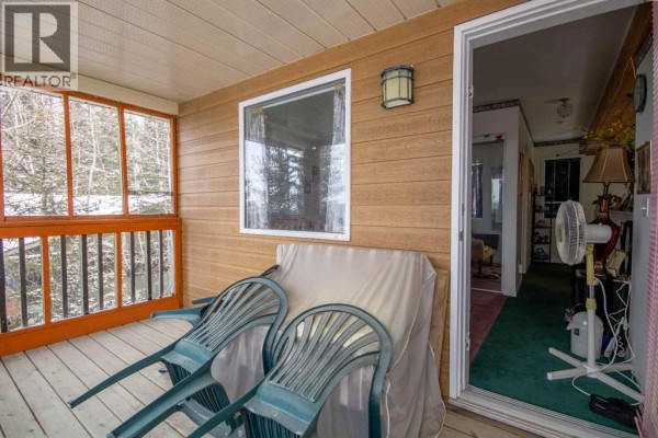 A wooden cabin with a screened porch and a separate small cabin are nestled amongst pine trees in the snow. - 99, 5227 Township Road 320, Rural Mountain View County