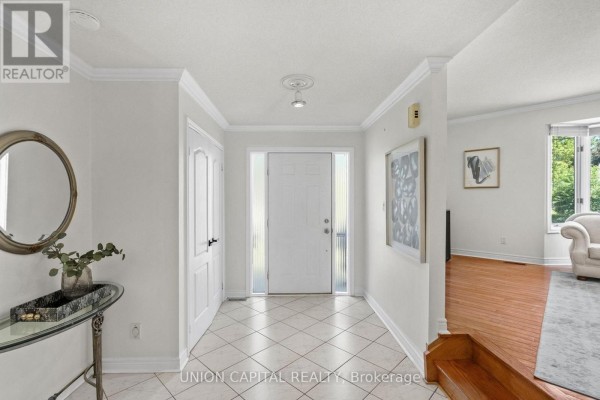 Interior hallway with tiled floor, curved wooden staircase with carpet runner. - 99 Abitibi Avenue, Toronto