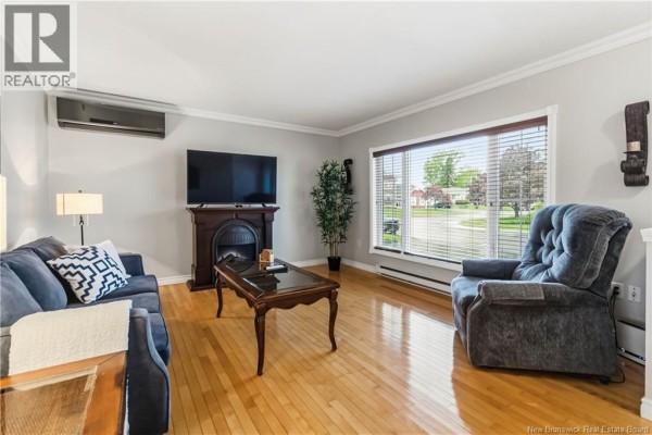 Living room with light grey walls, a dark blue sofa, a matching armchair, and a wooden coffee table. - 99 Fairview Knoll Drive, Moncton