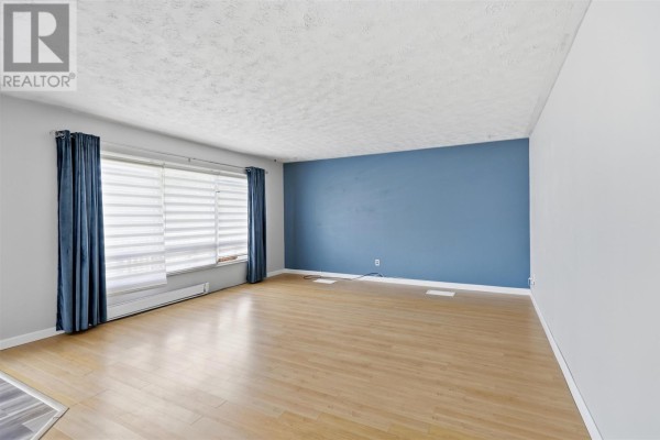 Living room with light wood laminate flooring and large windows with white blinds. - 99 Findlay Rd E, Echo Bay