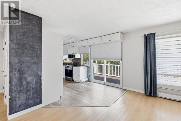 Living room with light wood laminate flooring, a blue accent wall, and a wooden hutch. - 99 Findlay Rd E, Echo Bay