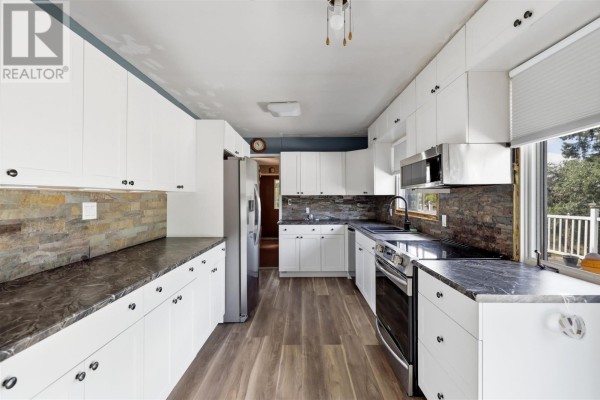 Kitchenette and dining area with sliding glass doors opening to a deck overlooking trees. - 99 Findlay Rd E, Echo Bay
