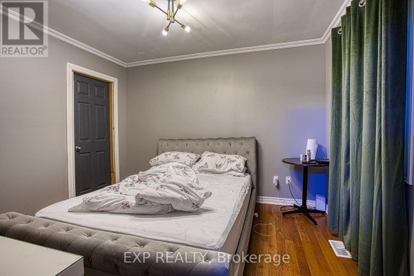 A bedroom with gray walls, a tufted gray bed with white bedding, a dark gray door, and green curtains. - 99 Mohawk Road W, Hamilton