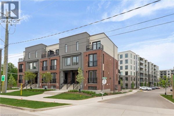 Street view of a row of townhouses and apartment buildings, showing a street corner and sidewalk. - 99 Roger Street Unit# 61, Waterloo