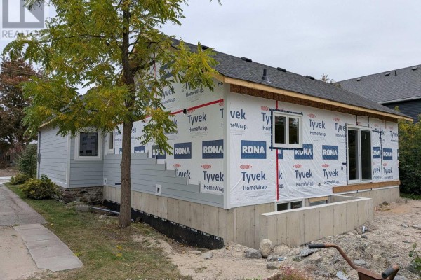 Side view of the house under construction, showing gray siding and windows. - 99 St Patrick Street, Kawartha Lakes