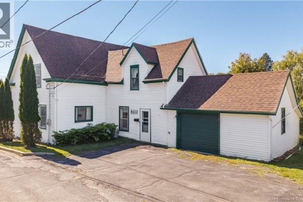 Side exterior view of a white house with green trim, a garage door, and a paved driveway. - 99 Union Street, St  Stephen
