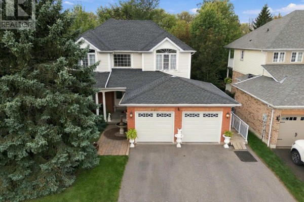 Aerial view of a two-story house with a double garage, driveway, and mature trees. - 990 Glenbourne Drive, Oshawa