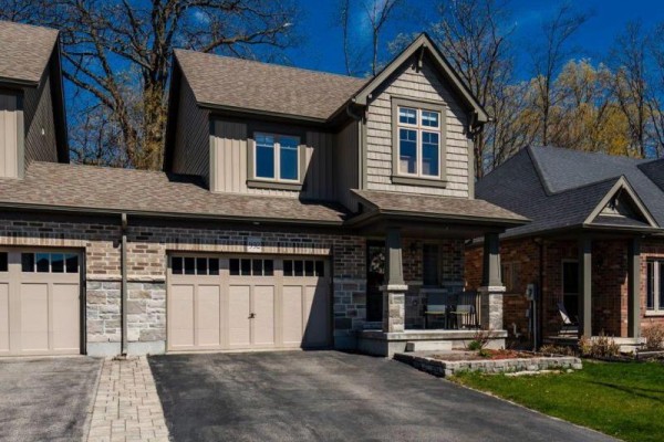 Front exterior of a townhouse with beige siding, stone accents, and a beige garage door. - 992 Cook Drive, Midland