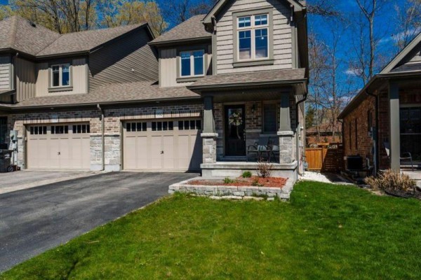 Close-up view of a townhouse exterior with brick and stone detailing and two garage doors. - 992 Cook Drive, Midland