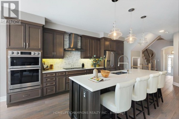 Modern kitchen with dark wood cabinets, stainless steel appliances, quartz countertops, and a large island with seating. - 993 Dragonfly Avenue, Pickering