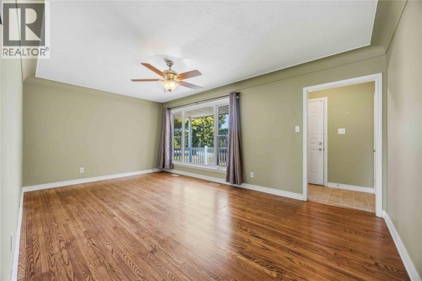 Living room with polished hardwood floors, a ceiling fan, and a large window overlooking the front yard. - 993 Highway Drive Unit# Upper, Sarnia