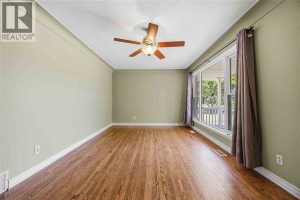 Living room with polished hardwood floors, a ceiling fan, and a large window with dark curtains. - 993 Highway Drive Unit# Upper, Sarnia