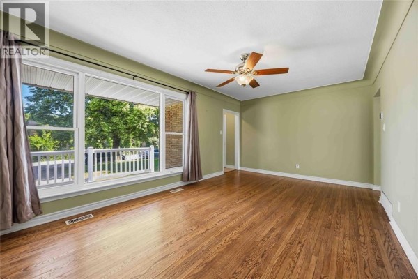 Living room featuring hardwood floors, a ceiling fan, and a wide window with a view of the porch. - 993 Highway Drive Unit# Upper, Sarnia