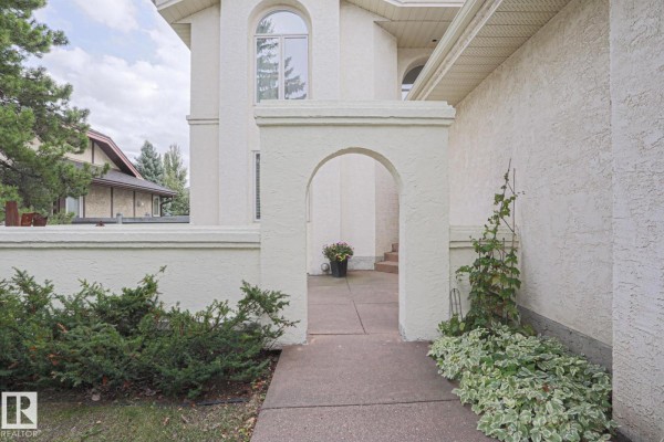 Covered entryway with white stucco archway and stone walkway. - 995 Ogilvie Bv Nw, Edmonton