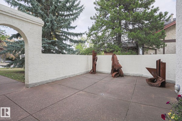 Paved patio area with abstract metal sculptures and white stucco wall. - 995 Ogilvie Bv Nw, Edmonton