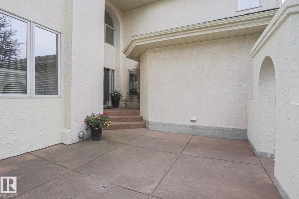 Concrete patio with textured stucco exterior walls and steps to entrance. - 995 Ogilvie Bv Nw, Edmonton