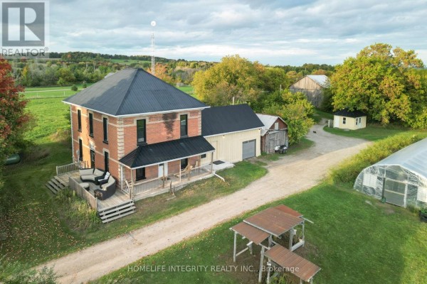 Aerial view of a red brick house surrounded by trees and green fields. - 995305 Mono Adjala Townline, Adjala Tosorontio