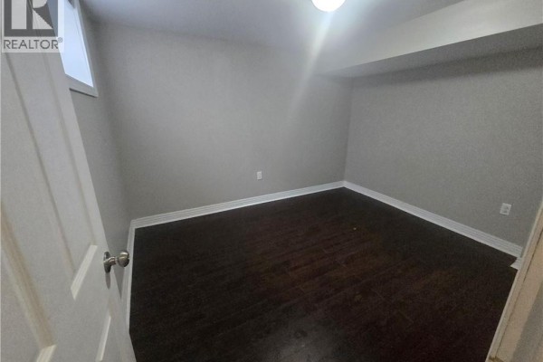 Empty room with dark wood floors and white trim. - 996 Queensdale Avenue E Unit# B, Hamilton