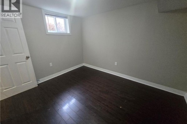 Empty room with dark wood floors and a window. - 996 Queensdale Avenue E Unit# B, Hamilton