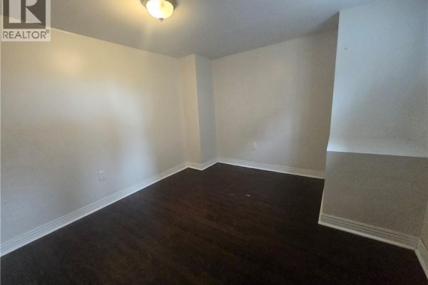 Empty room with dark wood floors and white walls. - 996 Queensdale Avenue E Unit# B, Hamilton