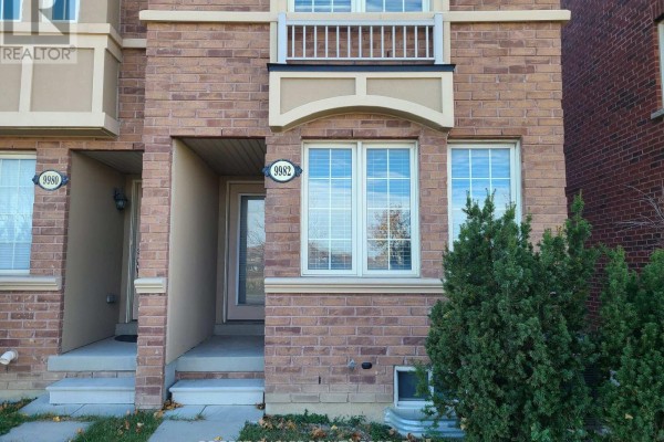 Front entrance of a townhouse with brick exterior, two windows, and covered doorway. - 9982 Mccowan Road, Markham